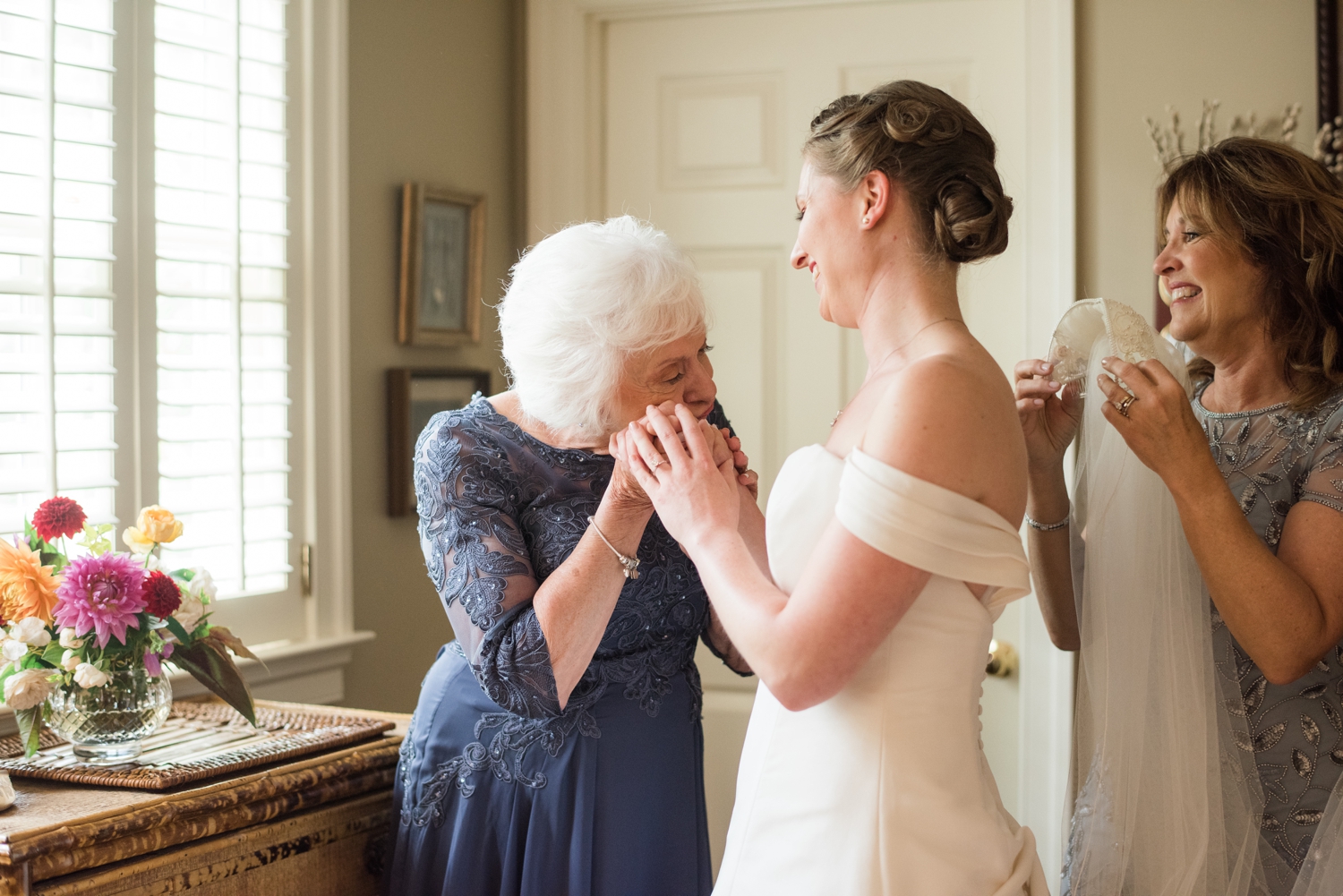 An elderly woman puts the bride's hand to her cheek