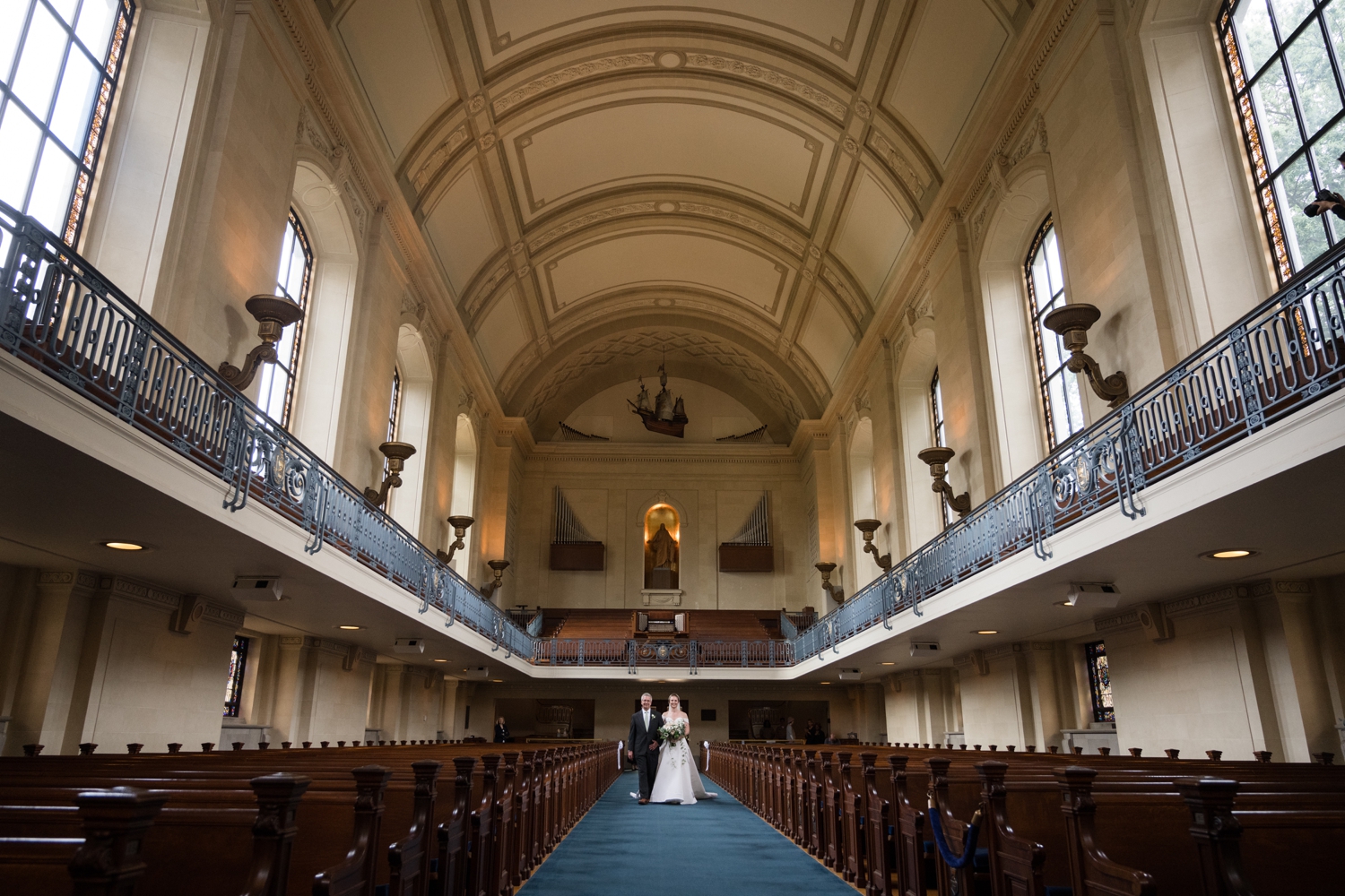 A wide shot of the bride going down the aisle with her father.