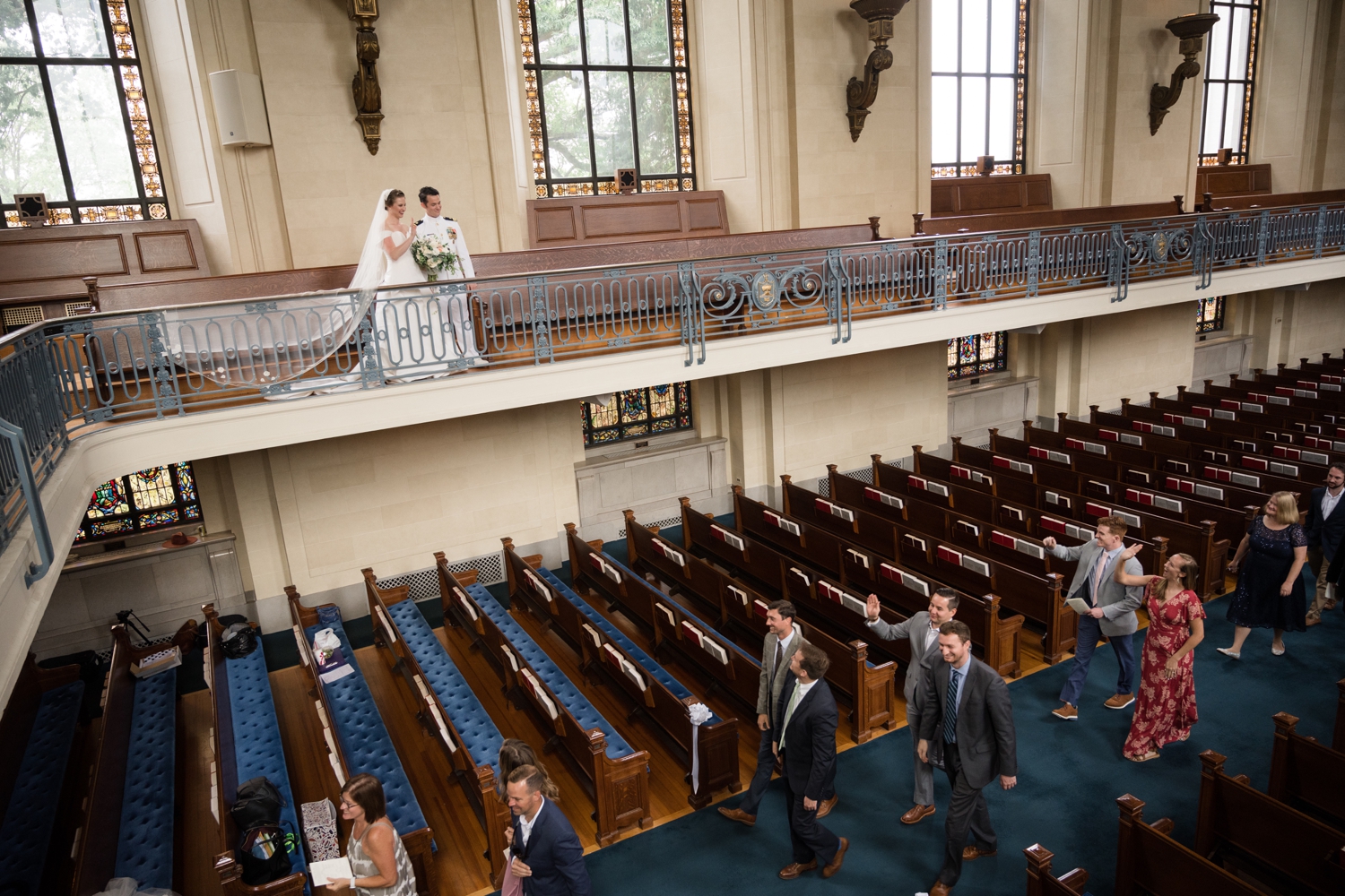 The bride and groom on the choir balcony as their bridal party recesses in the aisle below.