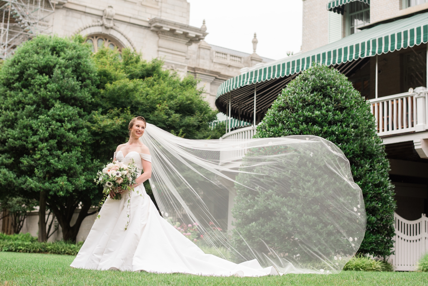 bride poses with her wind-swept veil to the right of her