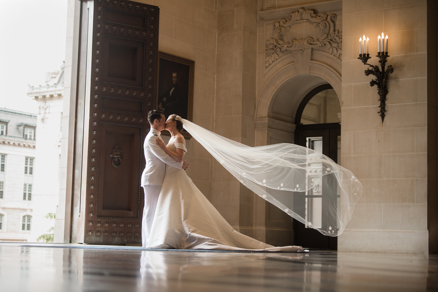 The bride and groom kiss in the Naval Chapel with her veil floating behind her.