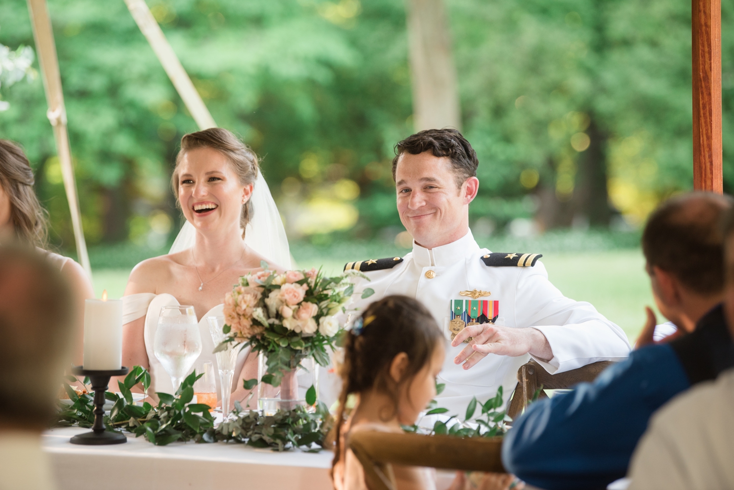 bride and groom smile while sitting together at the reception