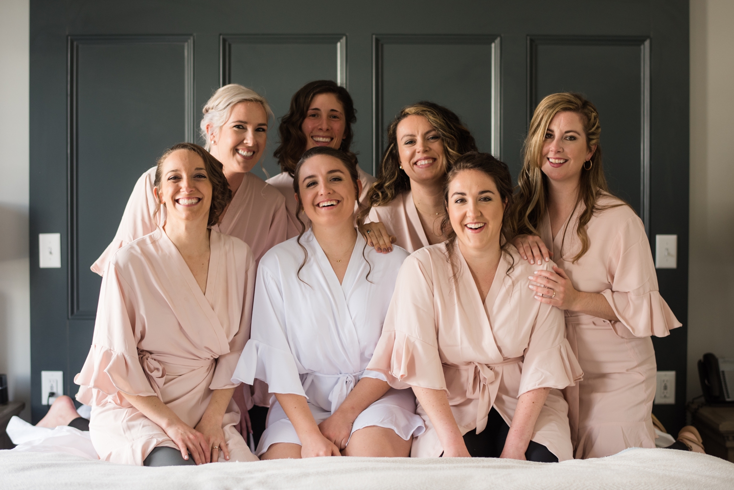 bridal party smiles on the bed together