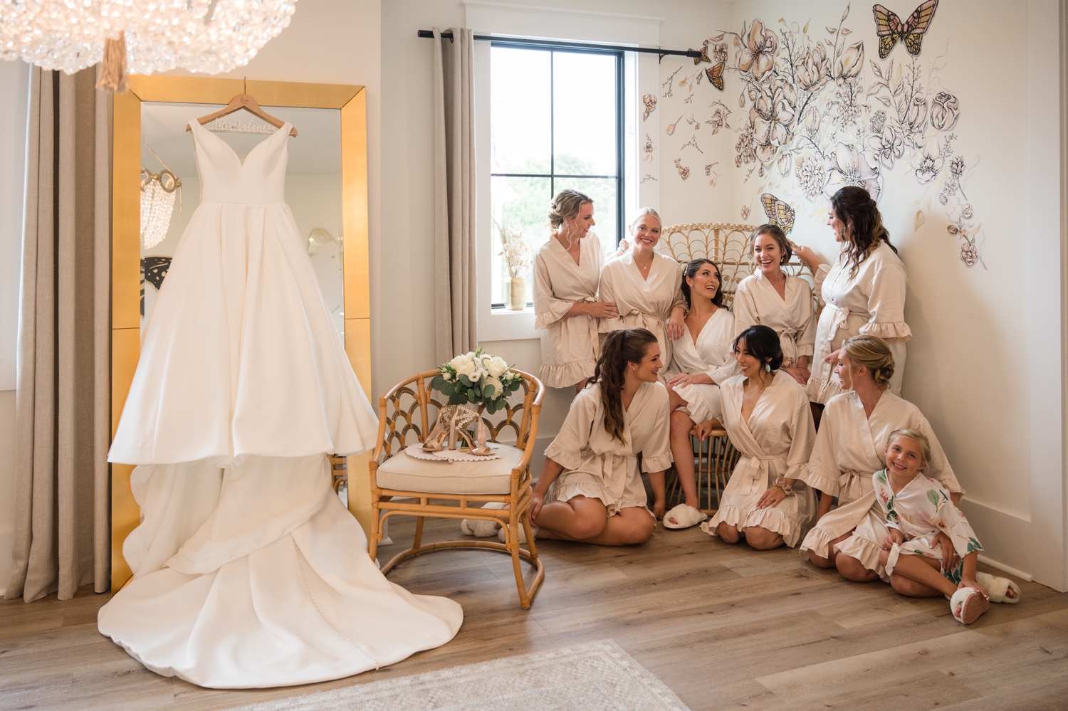 the bride and her bridesmaids gather while dress hangs beside them