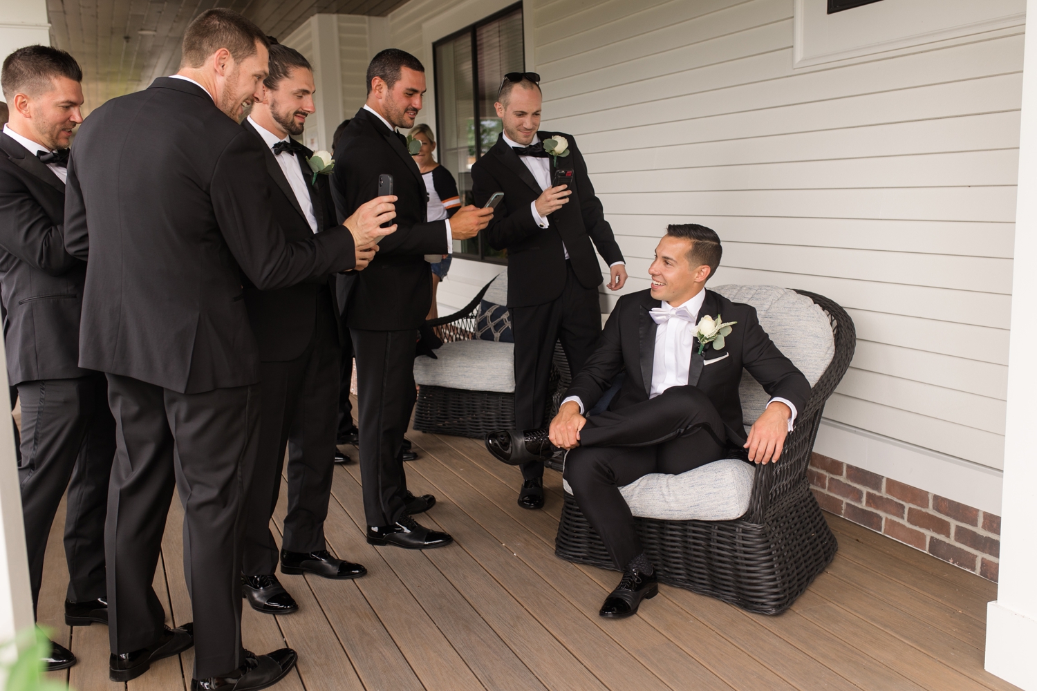 groomsmen take photos of the groom with their cellphones