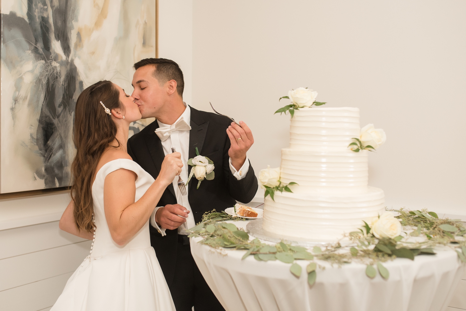 bride and groom kissing in front of cake