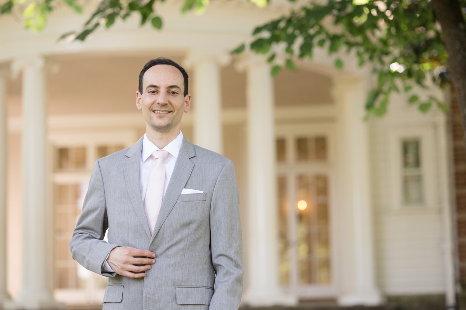 groom poses in front of Woodend Sanctuary & Mansion 