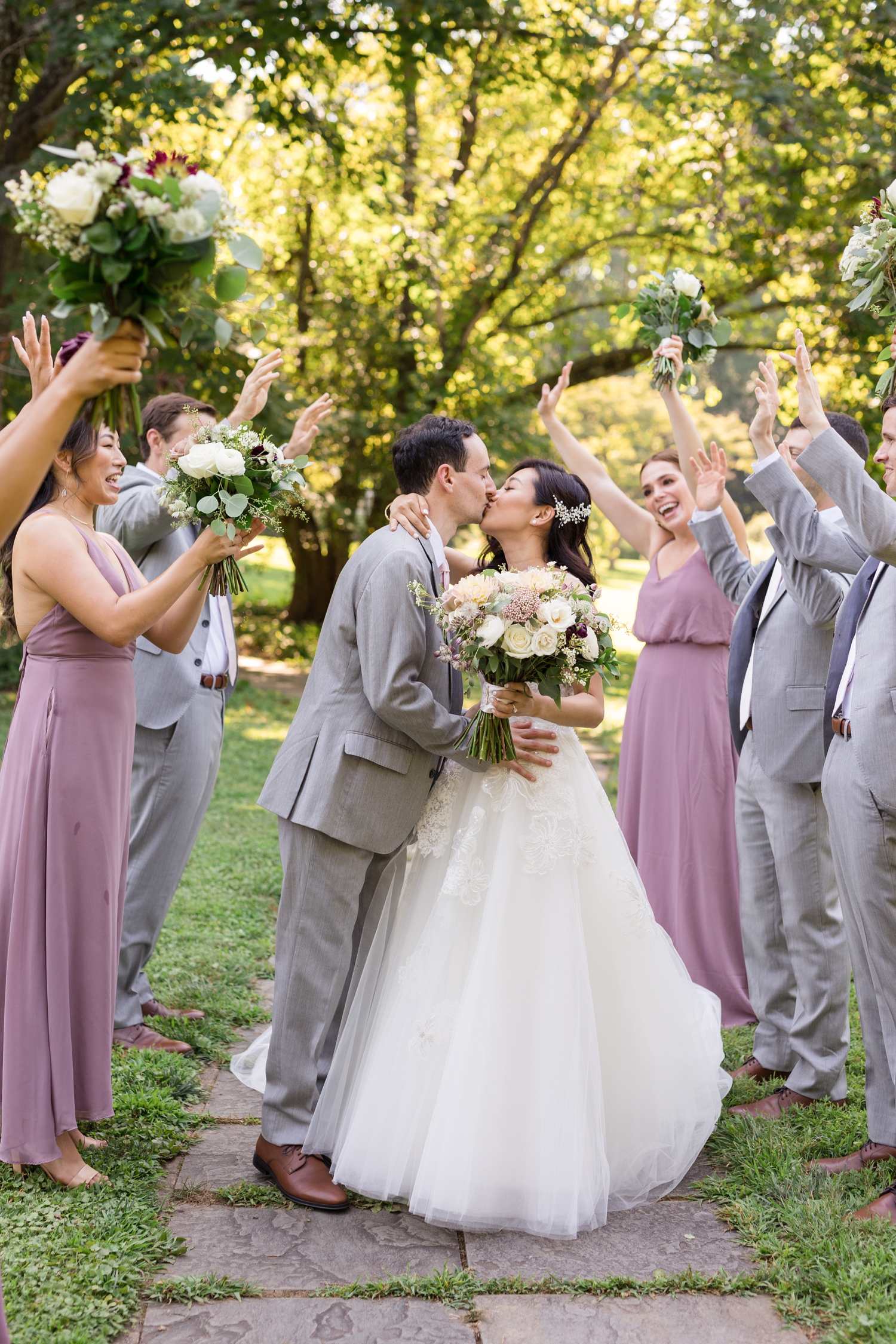 bride and groom share a kiss with bridal party on the grounds at Woodend Sanctuary & Mansion 