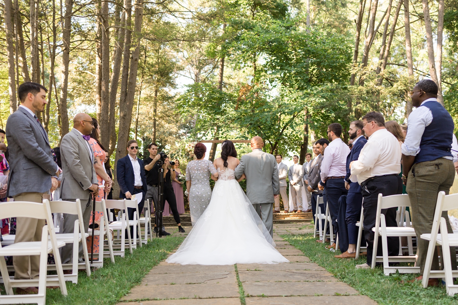 bride walks with her parents down the aisle for ceremony on the grounds at Woodend Sanctuary & Mansion 