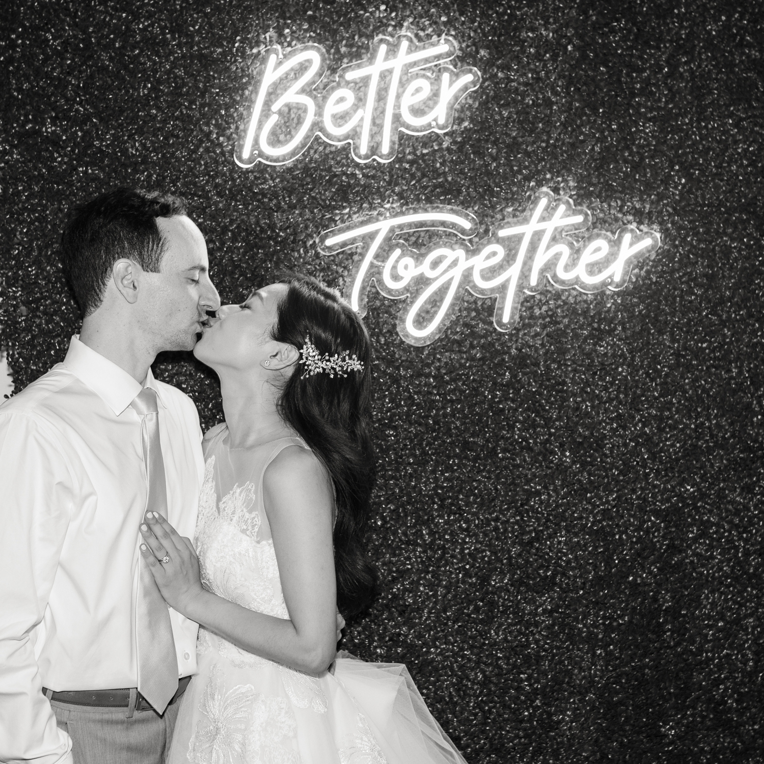 bride and groom kiss under neon sign at guests enjoy reception at Woodend Sanctuary & Mansion 