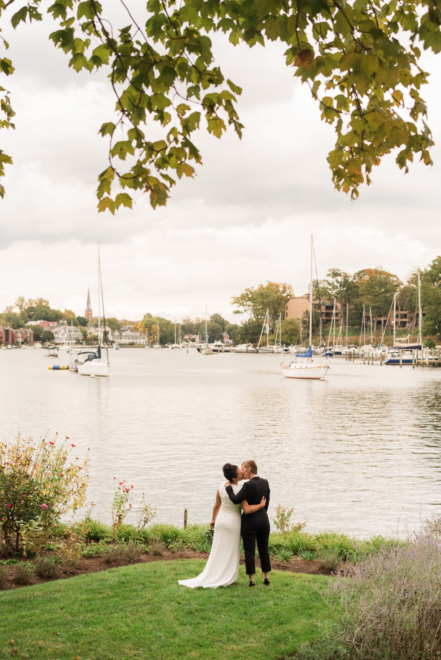 two brides white dress and black jumper suit overlooking Annapolis Bay