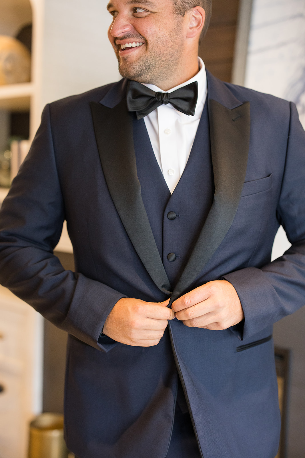 Groom buttoning his wedding suit jacket