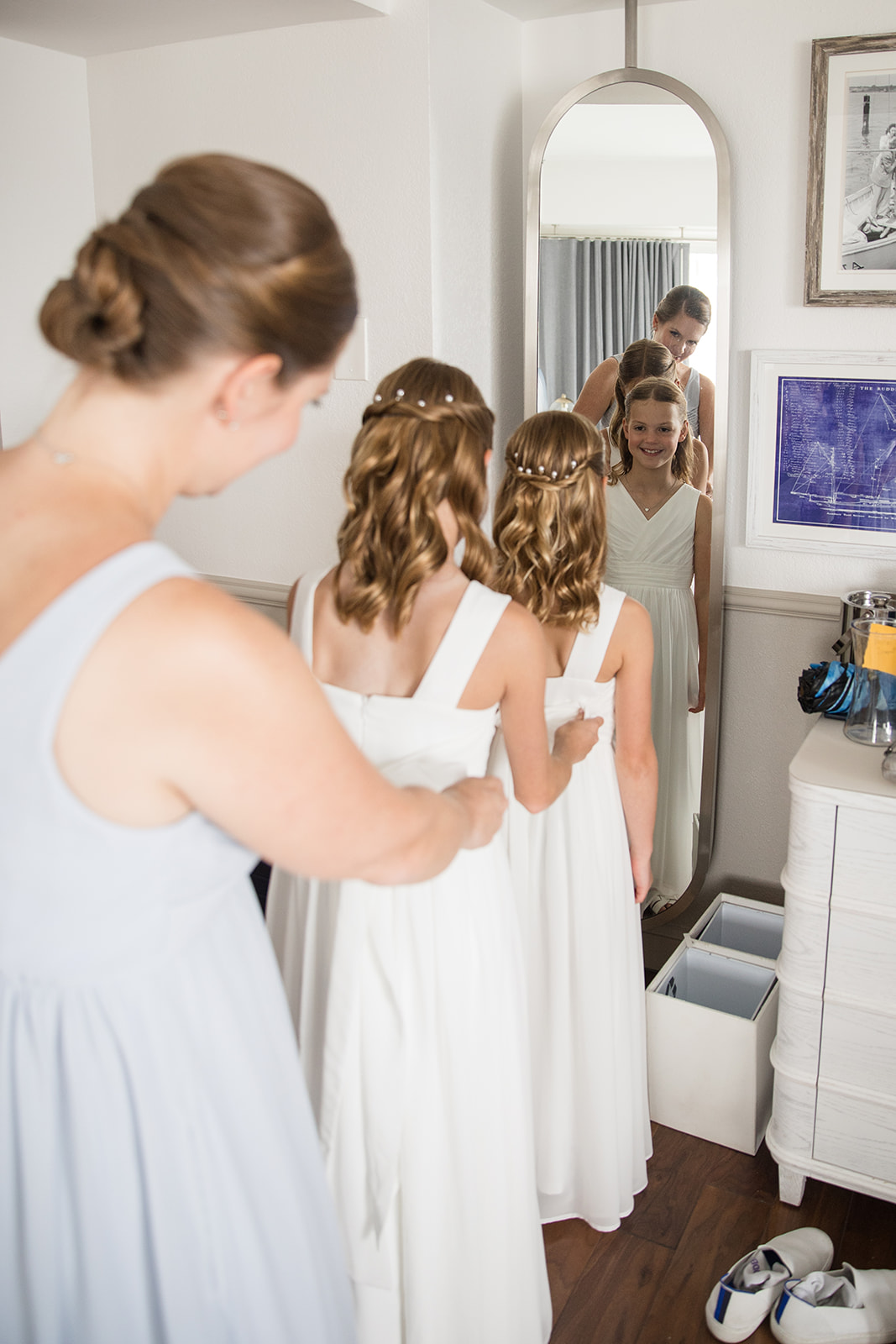 Bridesmaid helping flower girl get dressed