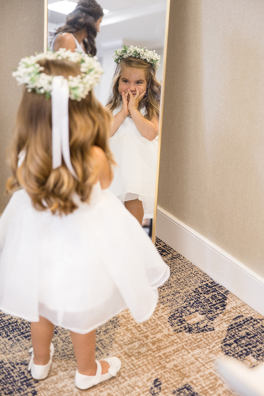 flower girl seeing herself in mirror with flower crown