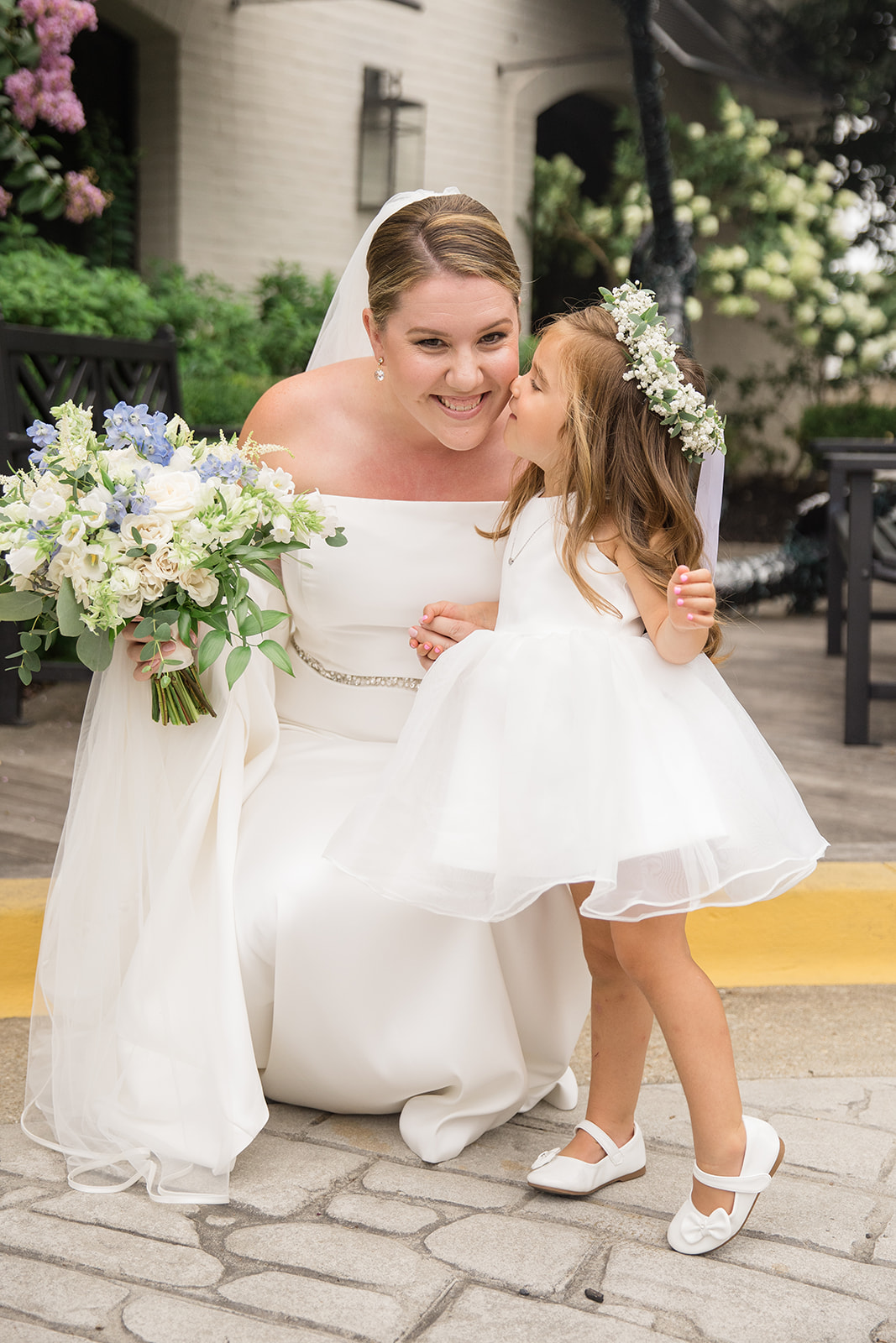 Flower girl giving bride a kiss on the cheek