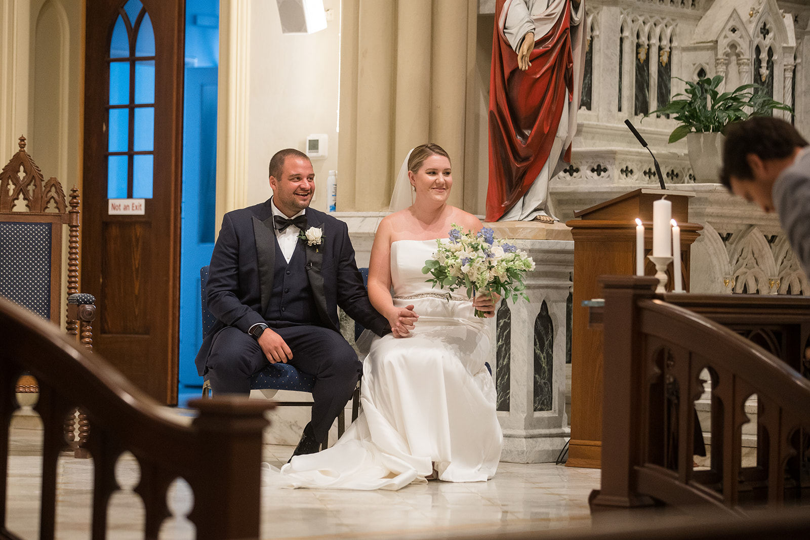 bride and groom sitting during catholic wedding ceremony