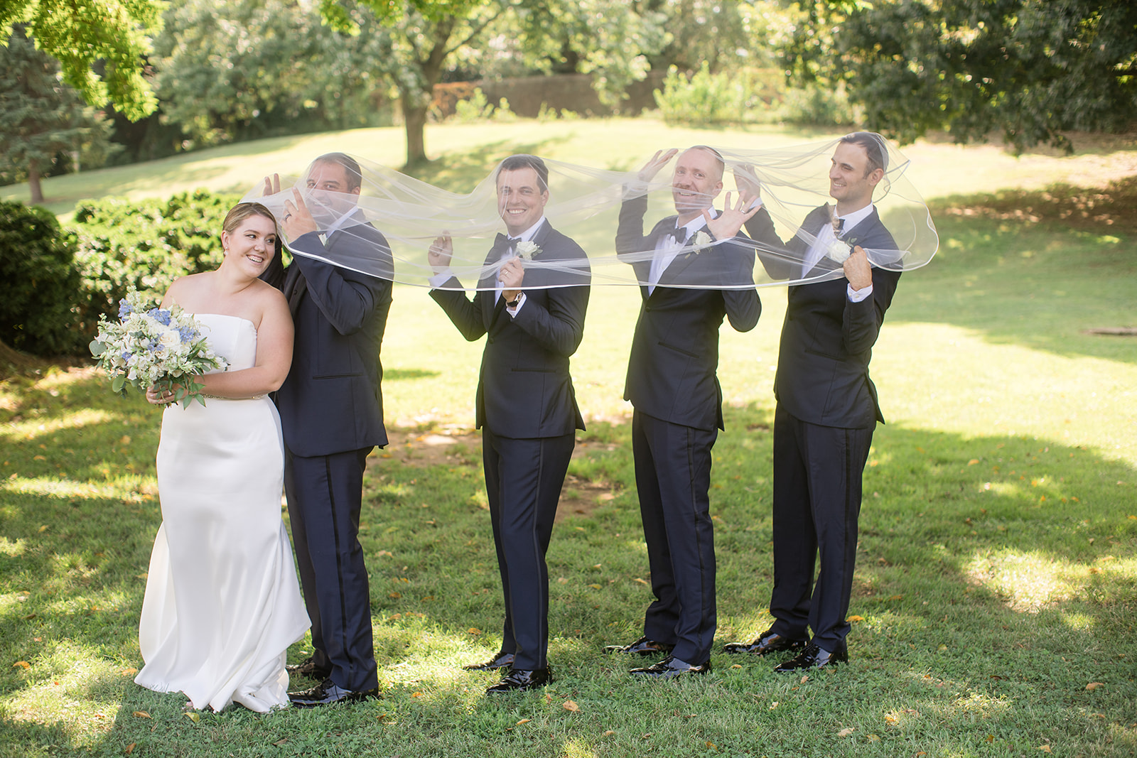 groomsmen being silly under bride's veil