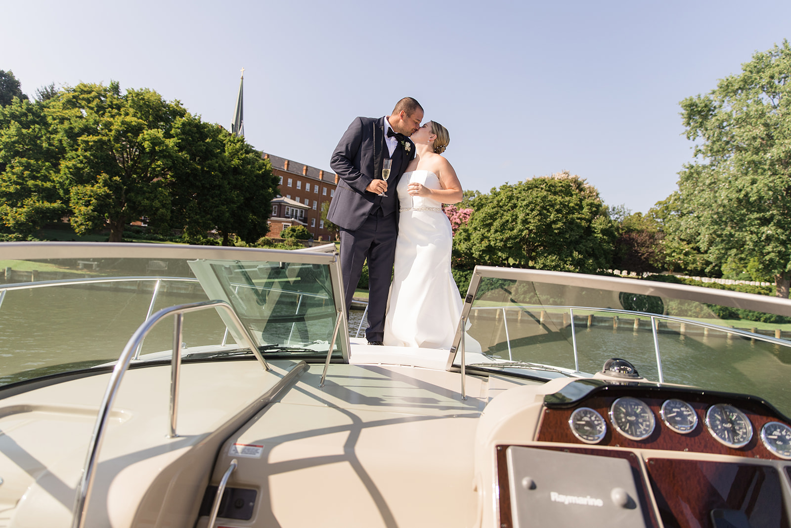 bride and groom kissing on bow of boat