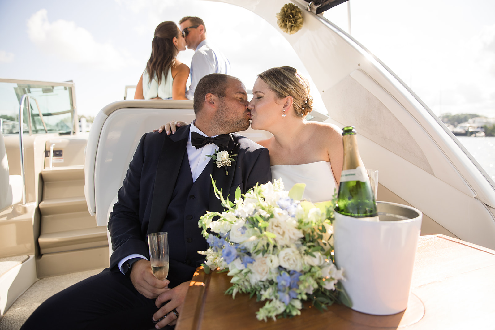 bride and groom kissing while sitting with drinks on a boat