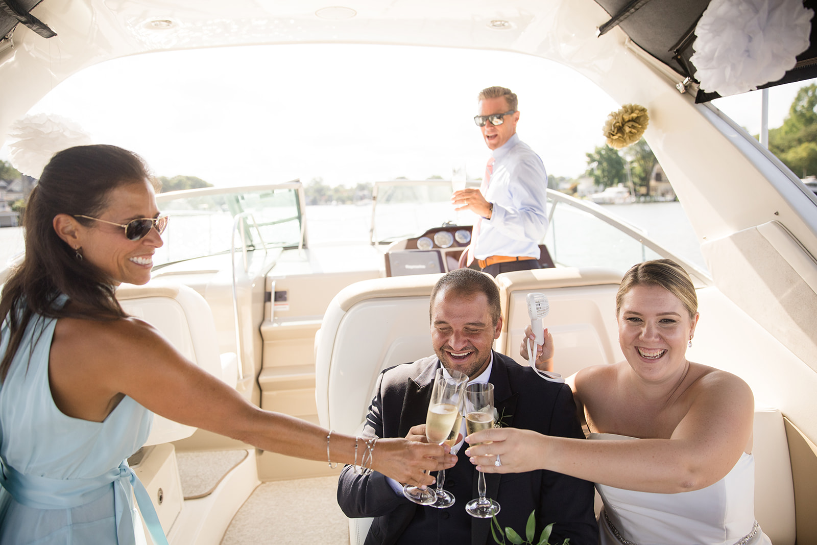 bride and groom cheersing while sitting on boat