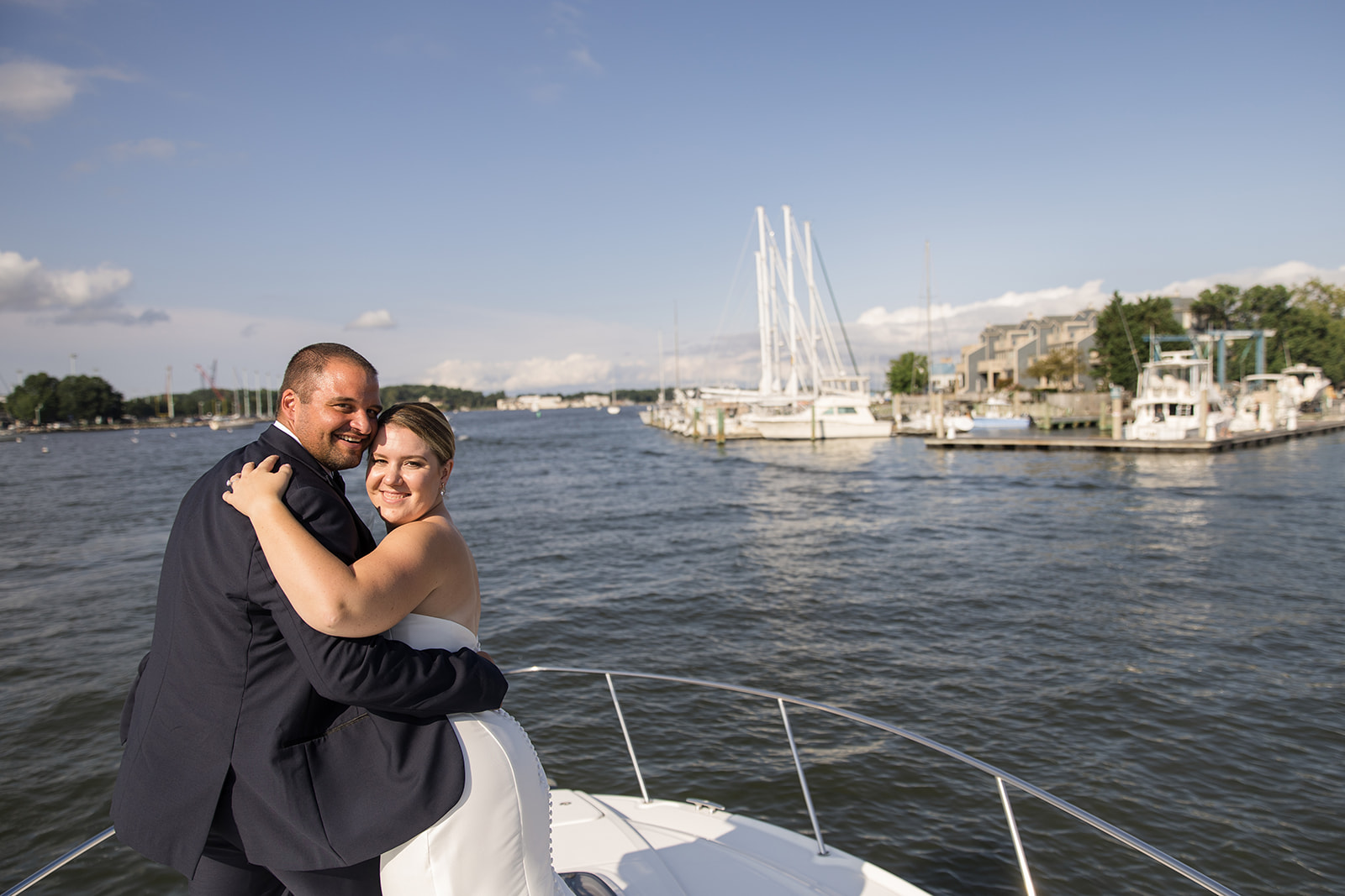 bride and groom on bow of boat looking back at camera