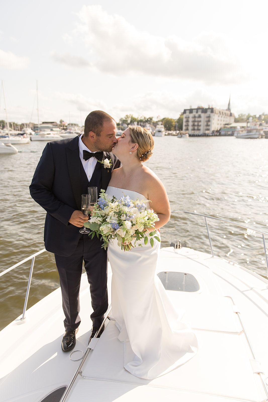 bride and groom kissing on bow of boat