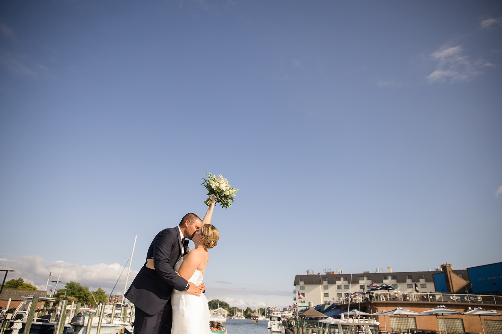 bride and groom kiss with bouquet in the air