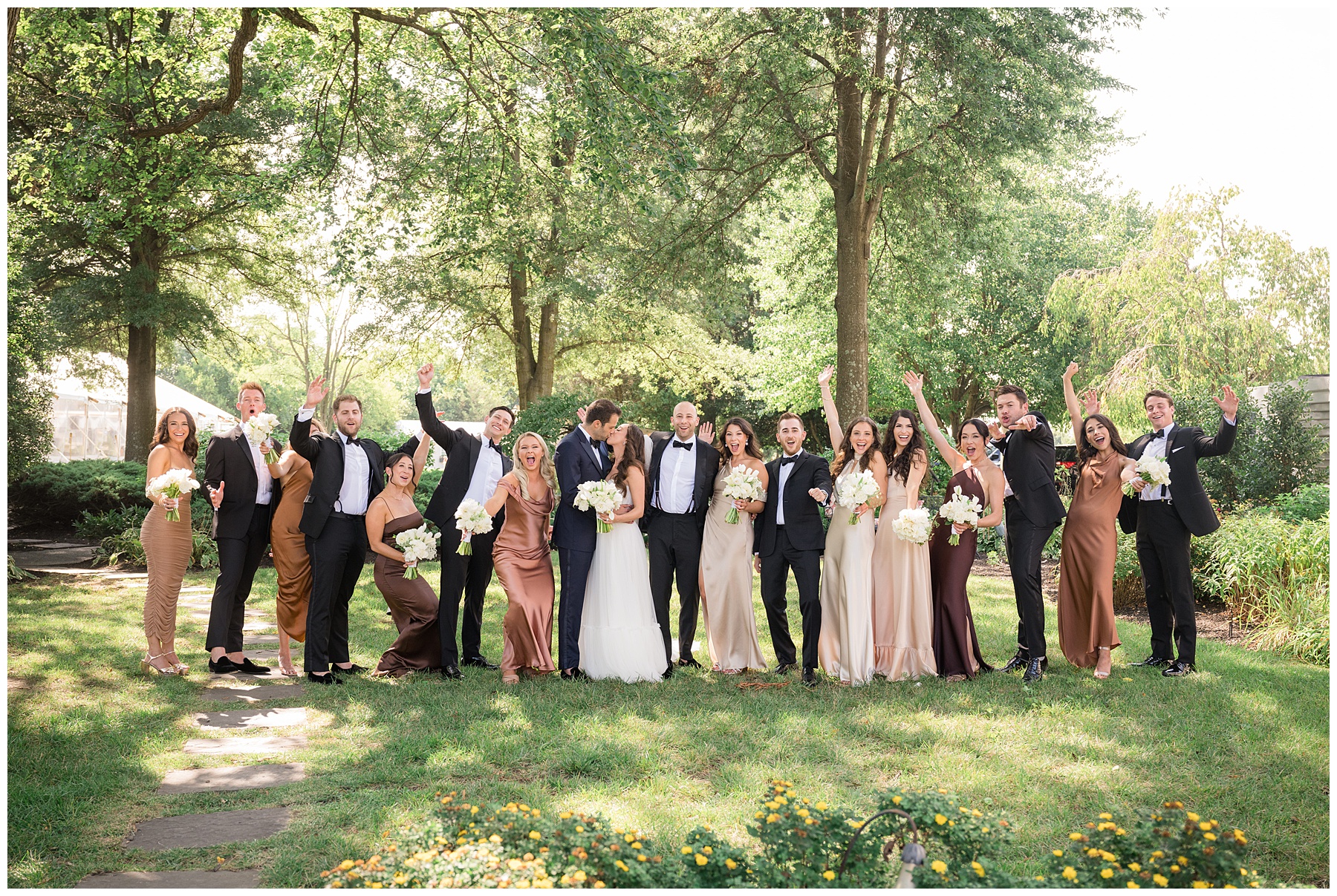 full wedding party cheering as couple kisses