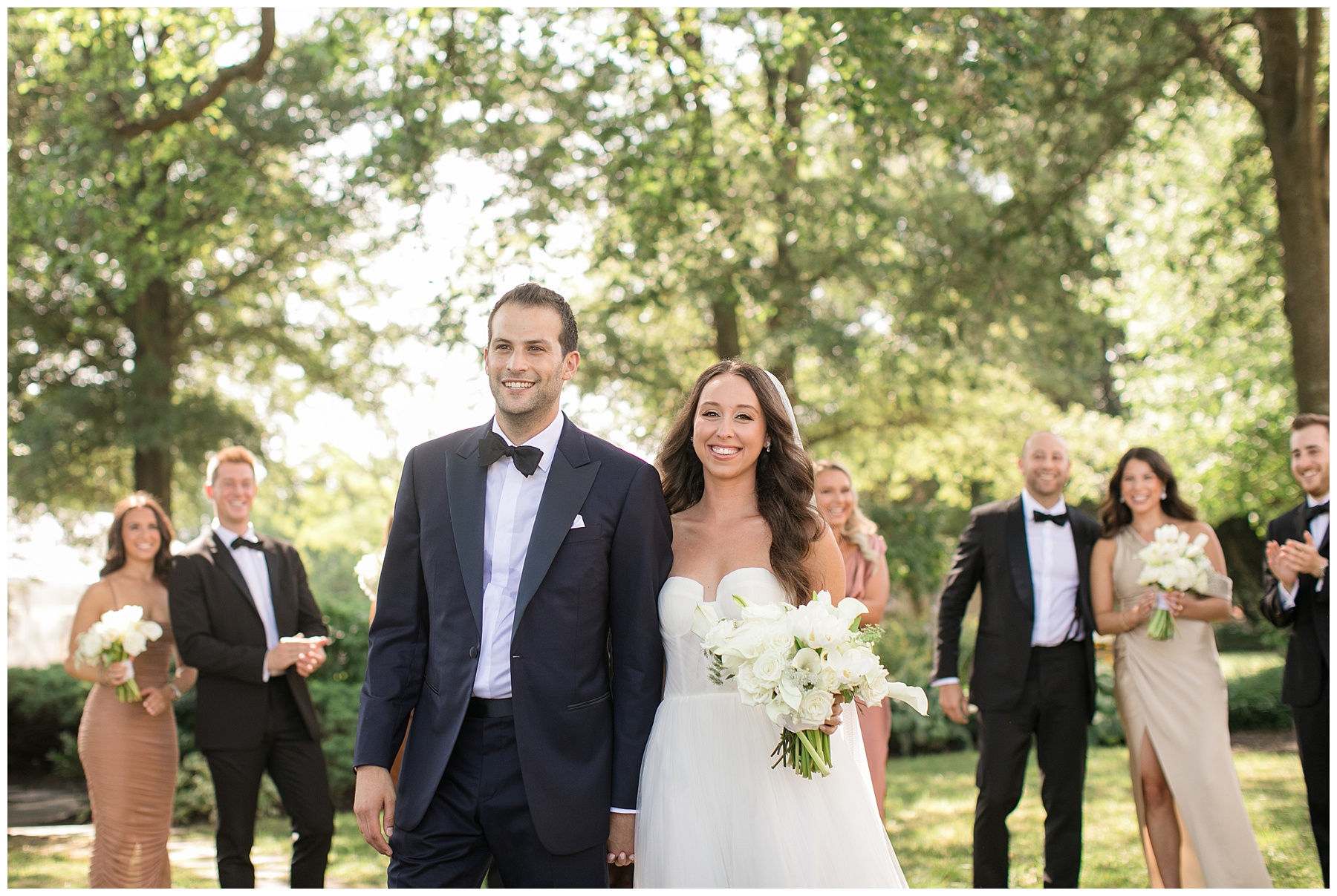 bride and groom walking with wedding party in background