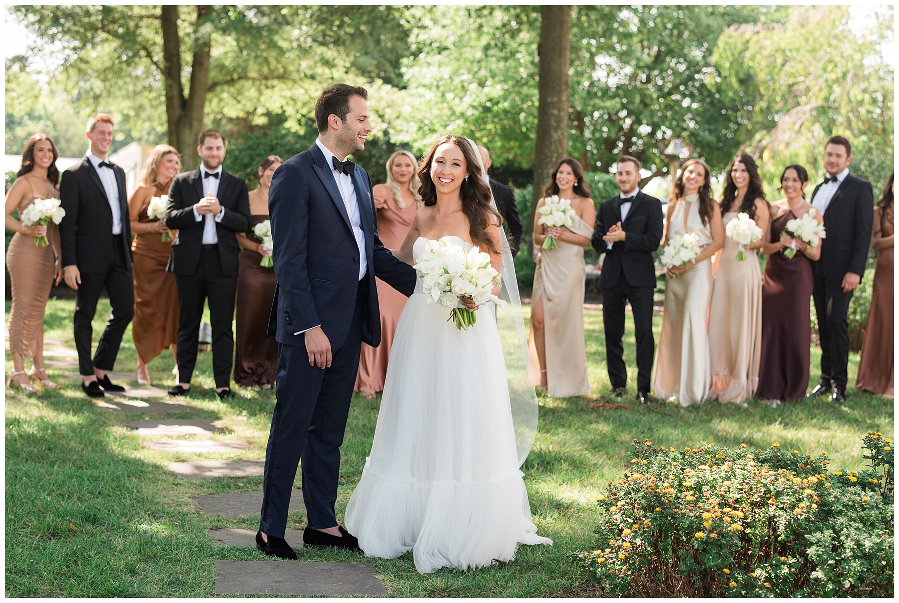 bride and groom walking with wedding party in background