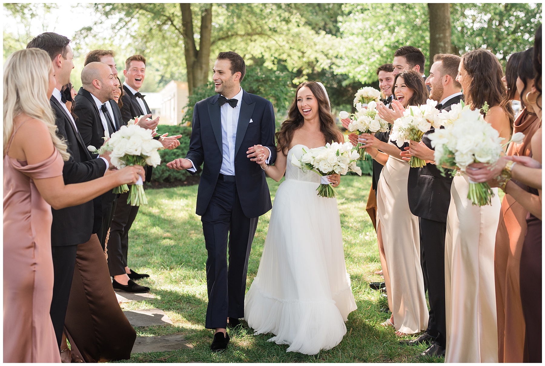 bride and groom walking with wedding party in background