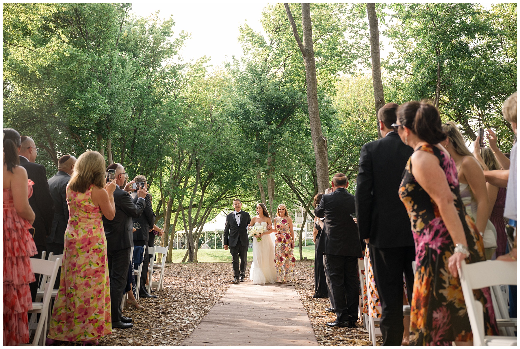 bride coming down aisle with parents outdoor wedding ceremony