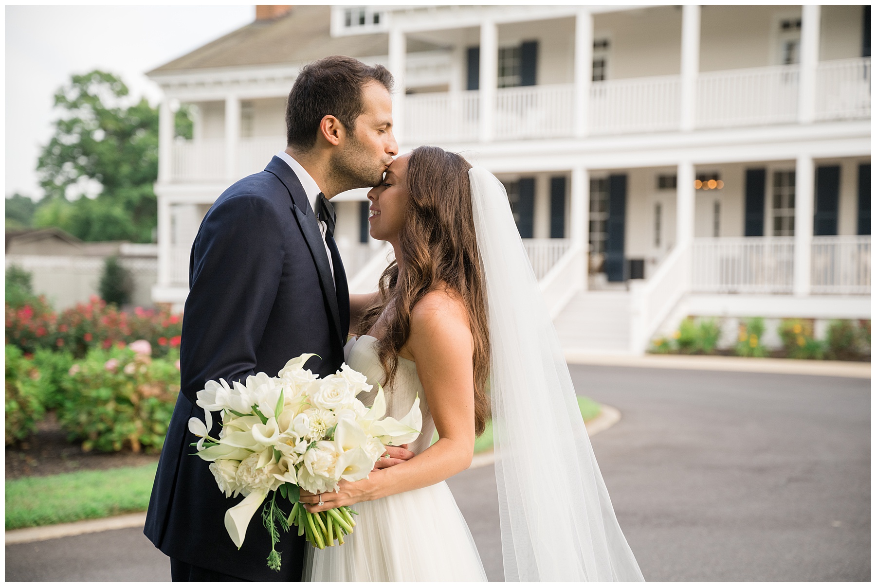 bride and groom forehead kiss in front of venue resort