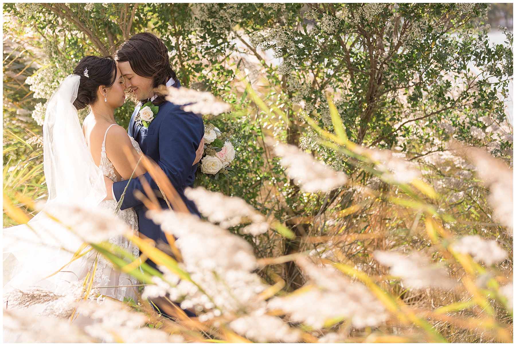 bride and groom embrace with bay reeds in forground