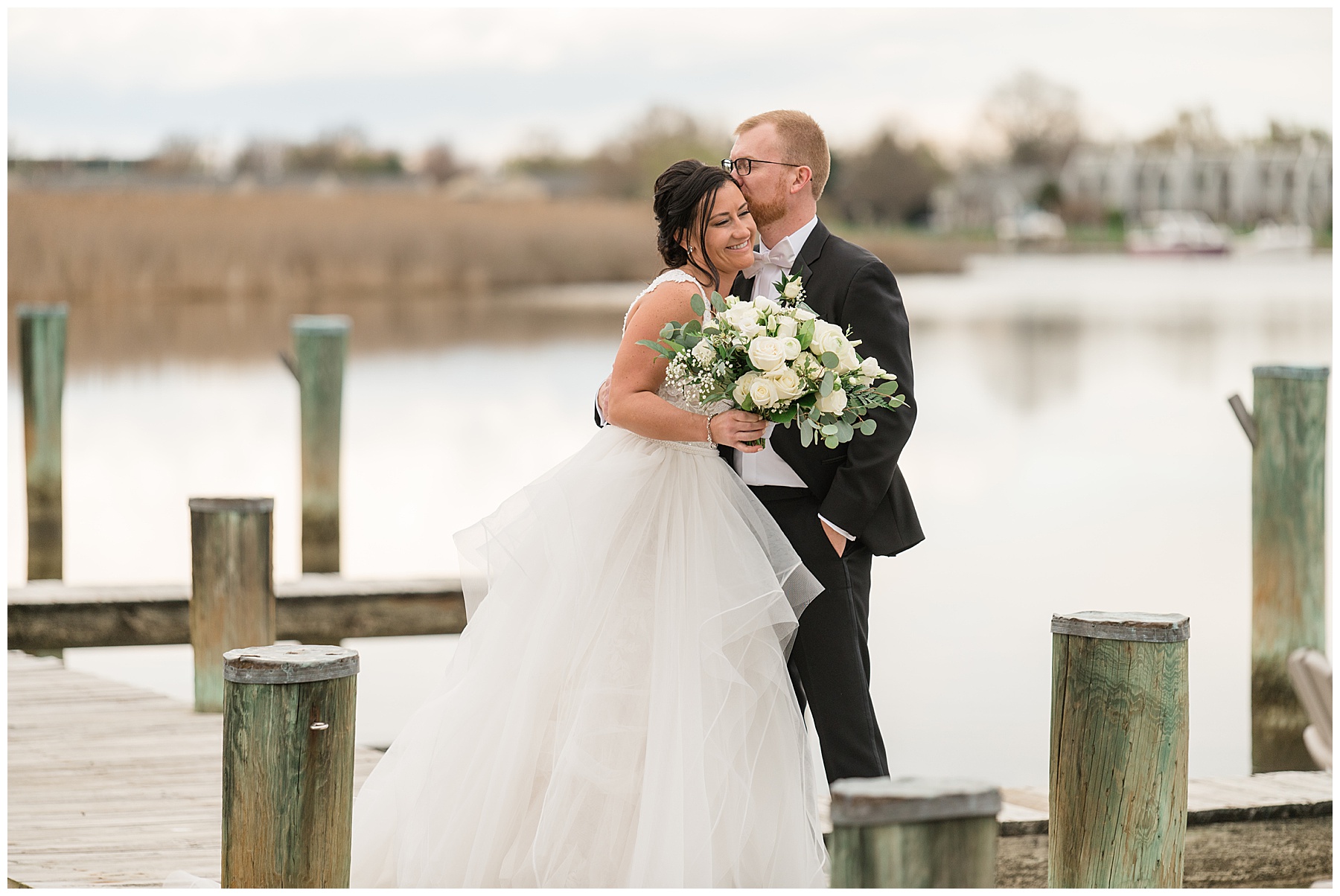 bride and groom embrace on kent island pier