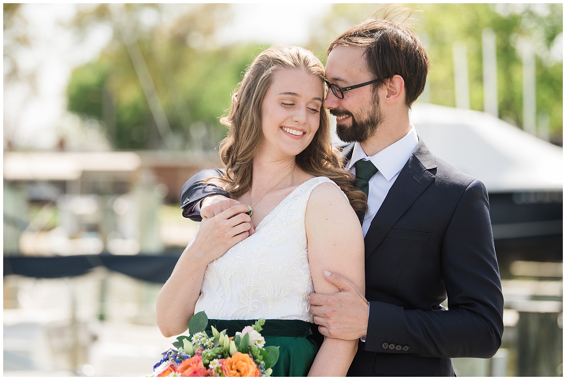 bride and groom embrace on pier