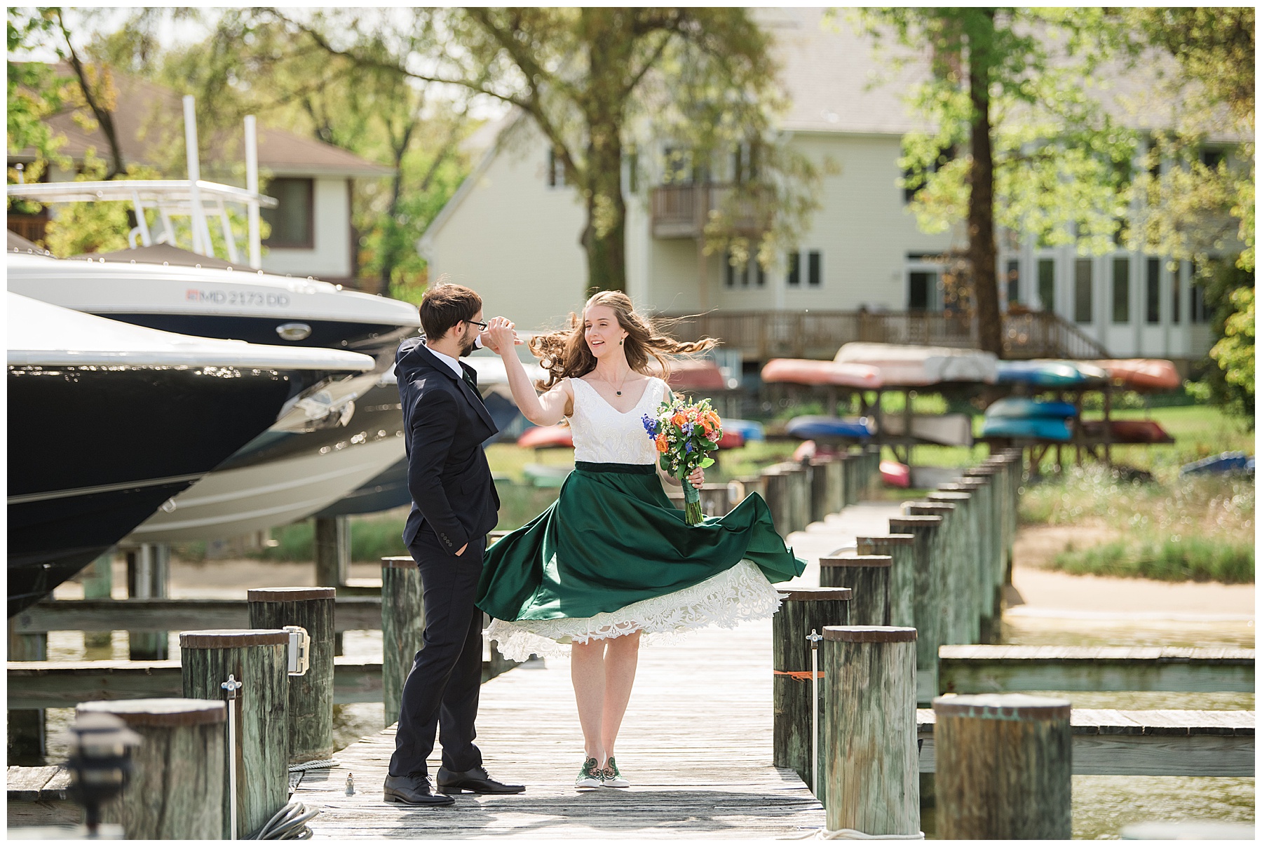 groom spins bride on pier green dress