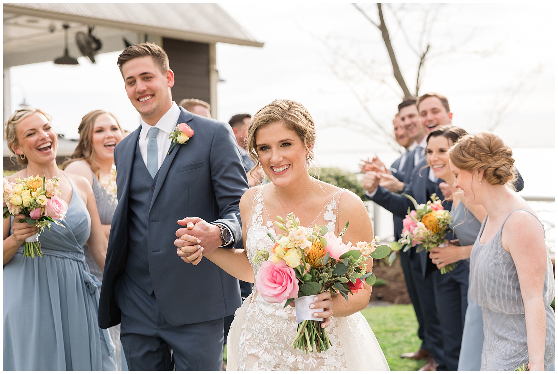 bride and groom laughing with wedding party