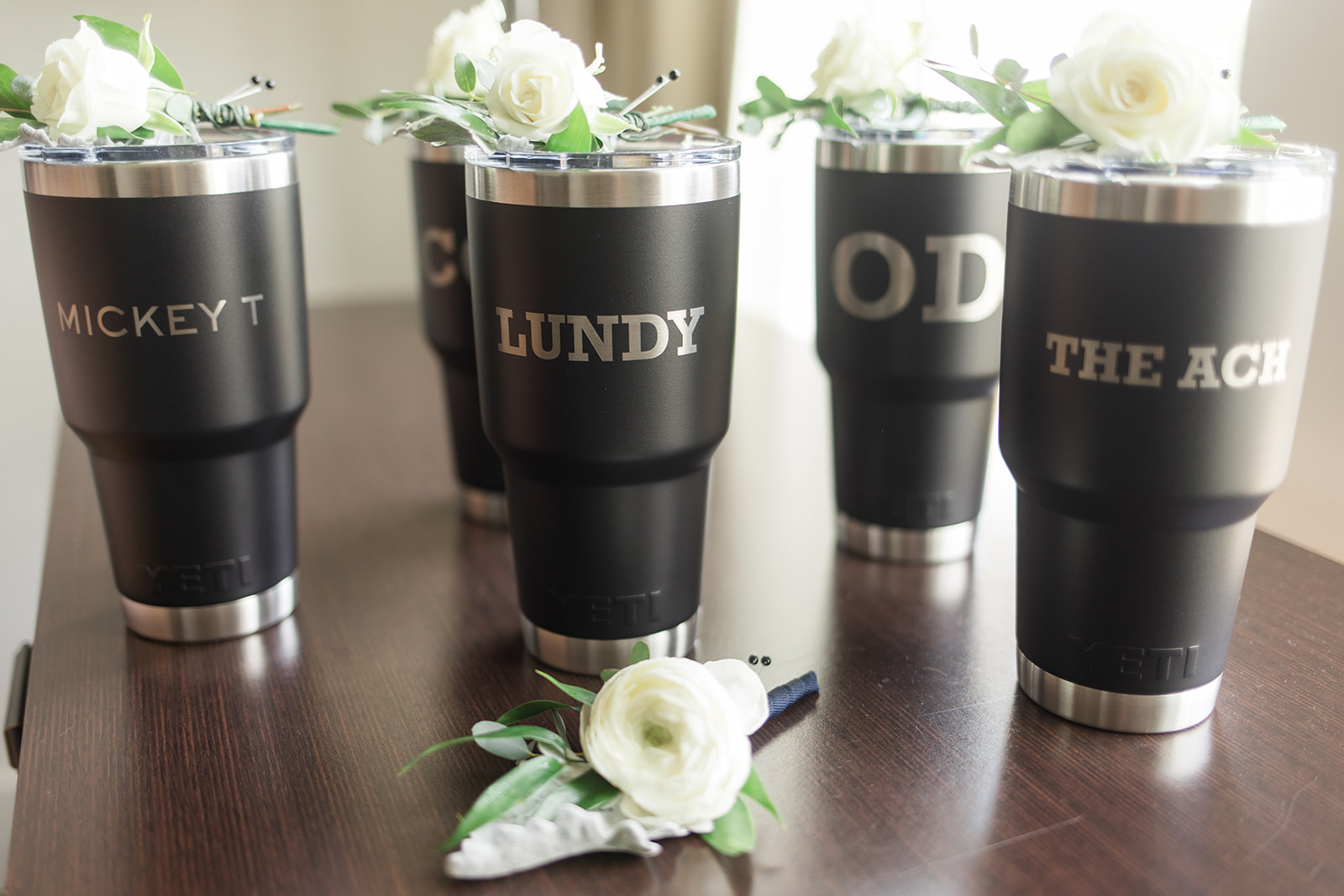 groomsmen boutonnieres sit on top of customized metal tumblers