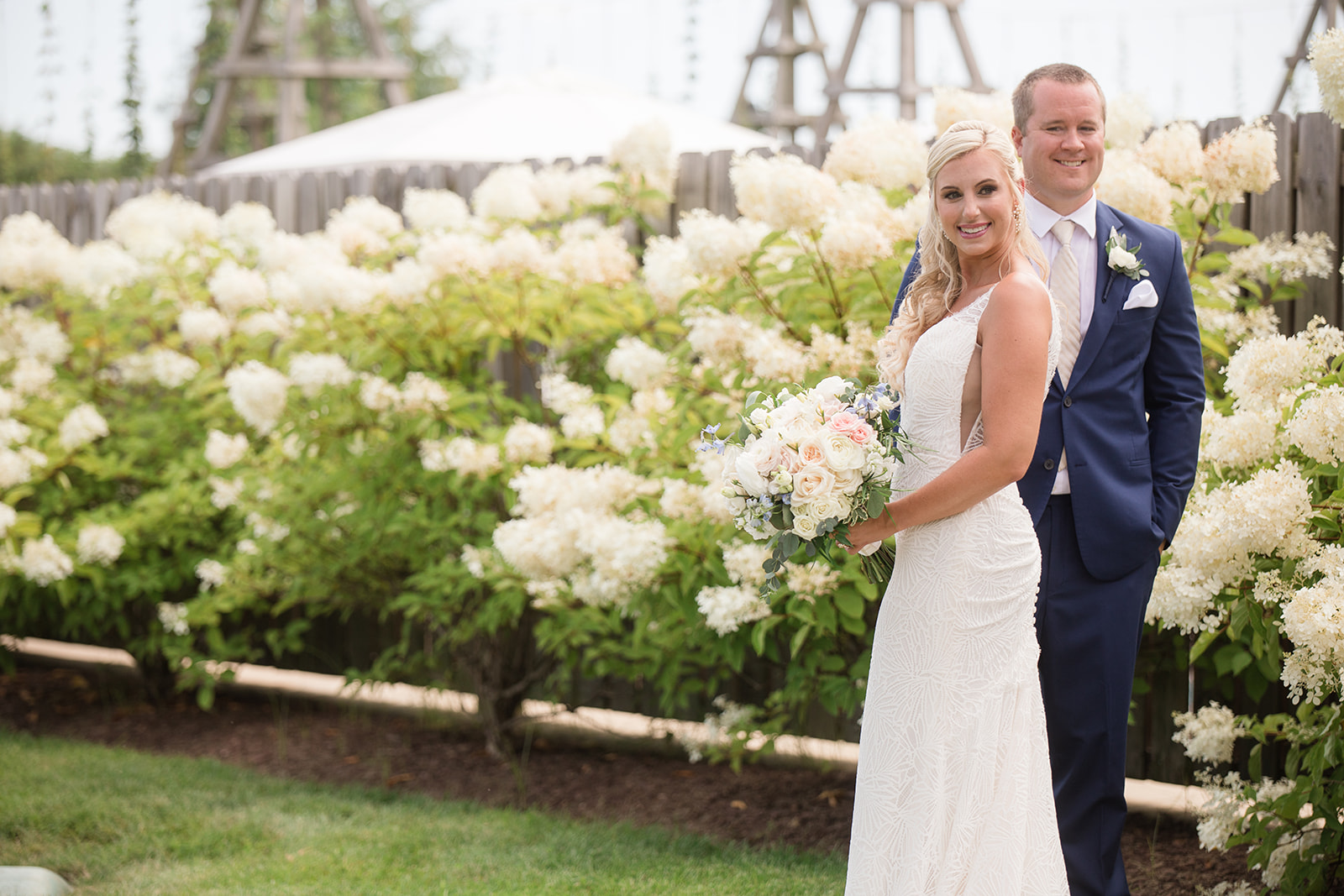 bride and groom in front of white flowering bushes