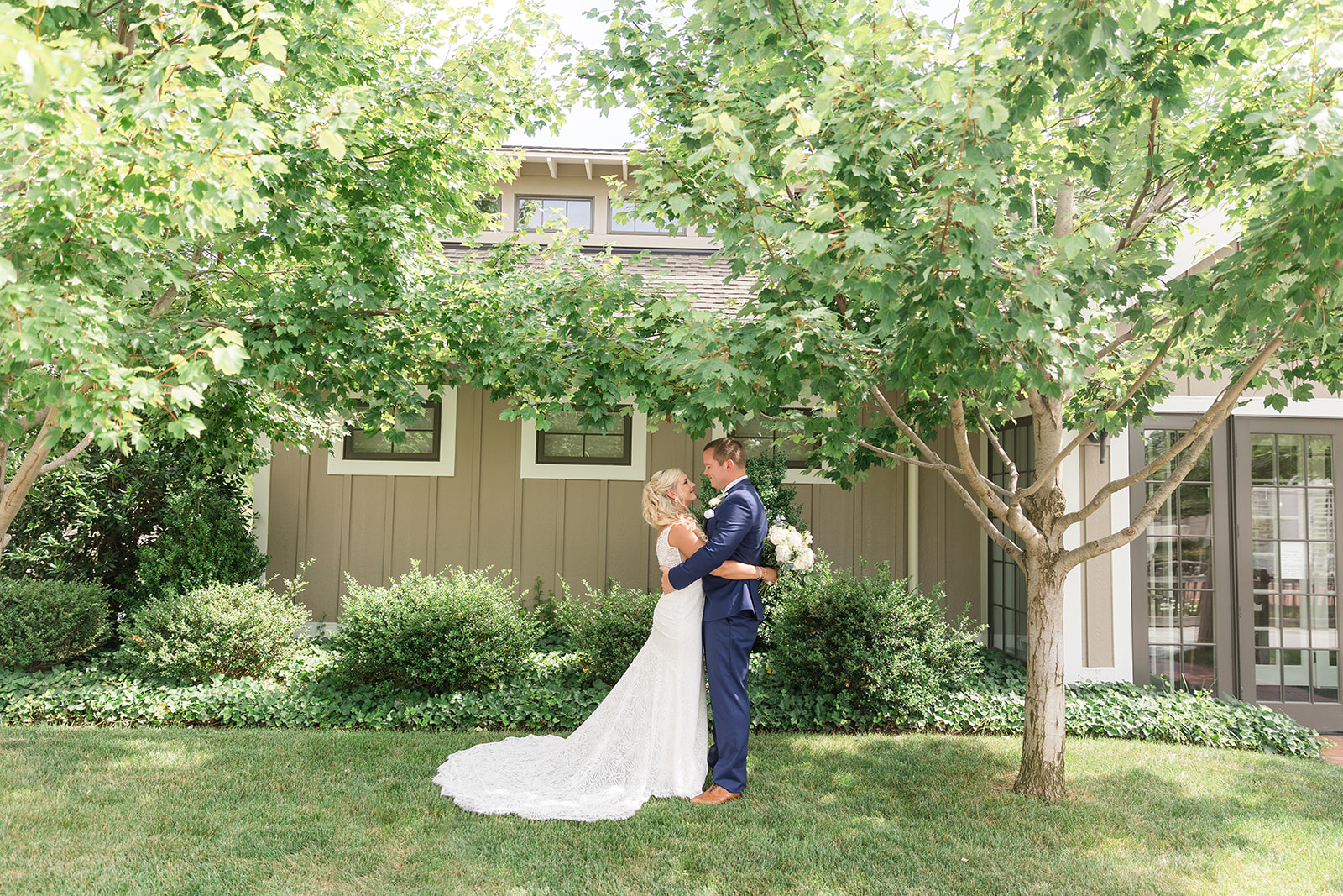 bride and groom embrace under trees