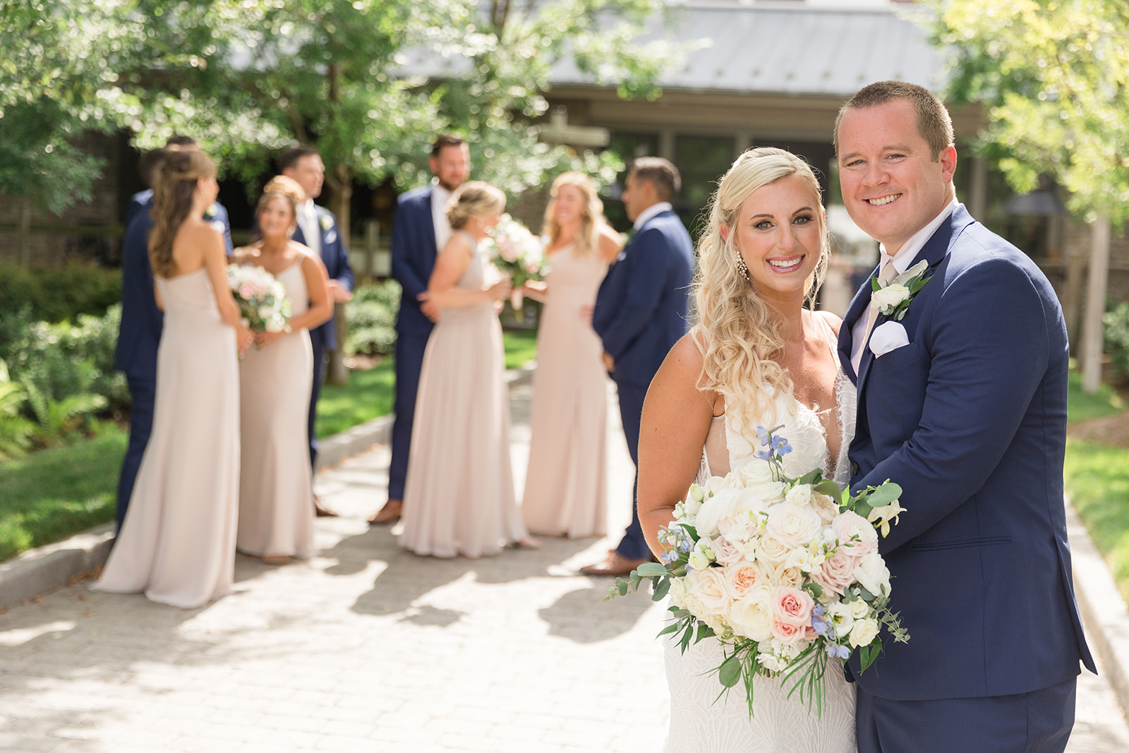 bride and groom smiling in foreground with wedding party behind them