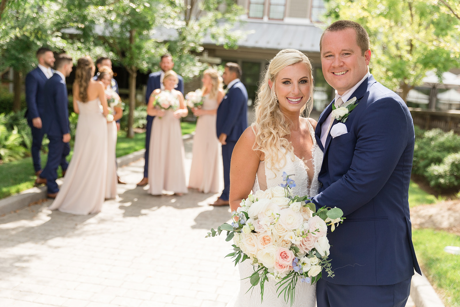 bride and groom smiling in foreground with wedding party behind them