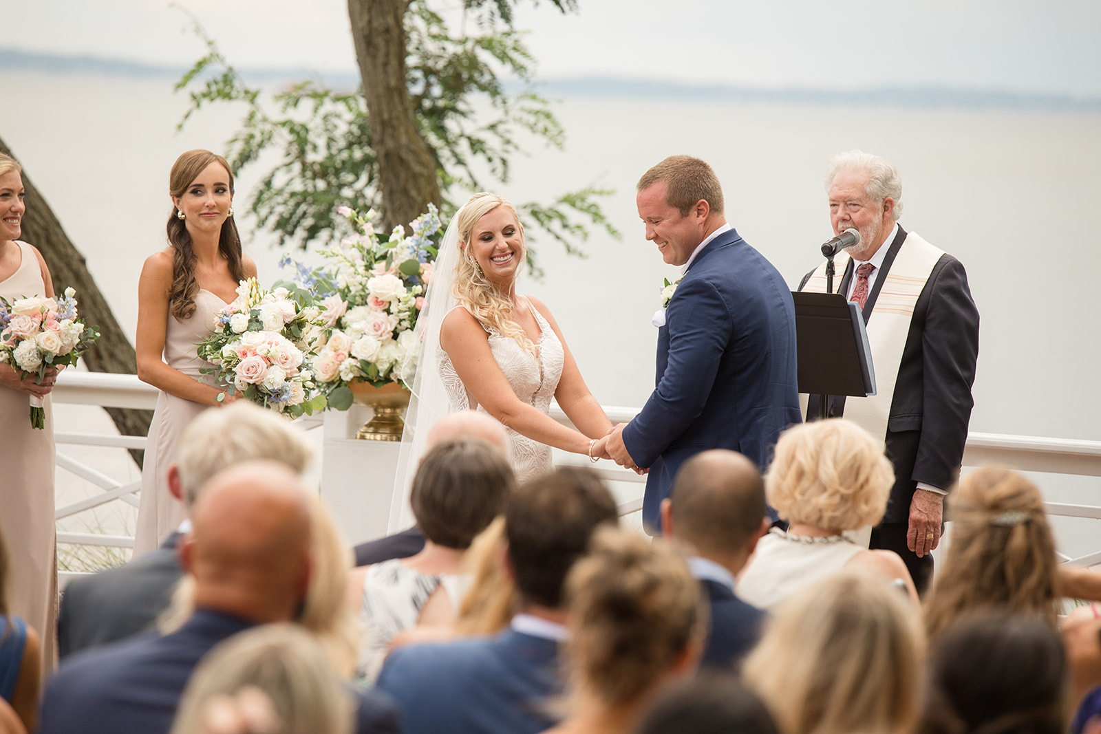 bride and groom hold hands during ceremony and laugh at guests