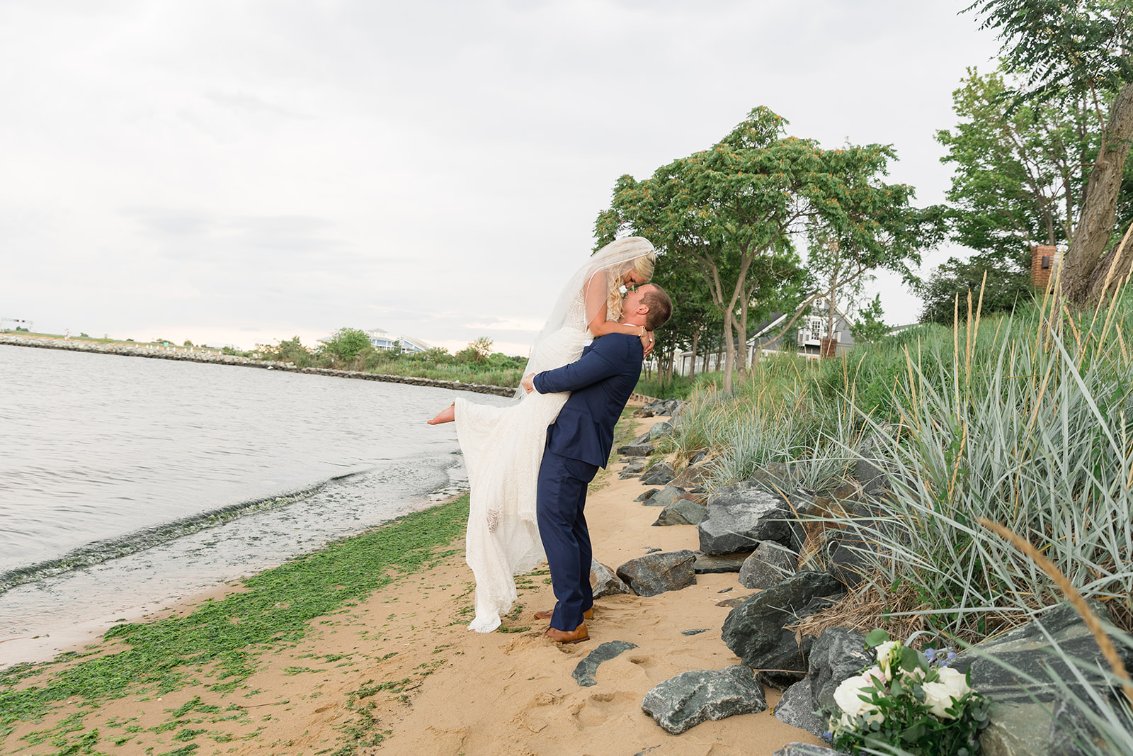 groom lifting and kissing bride on sandy beach