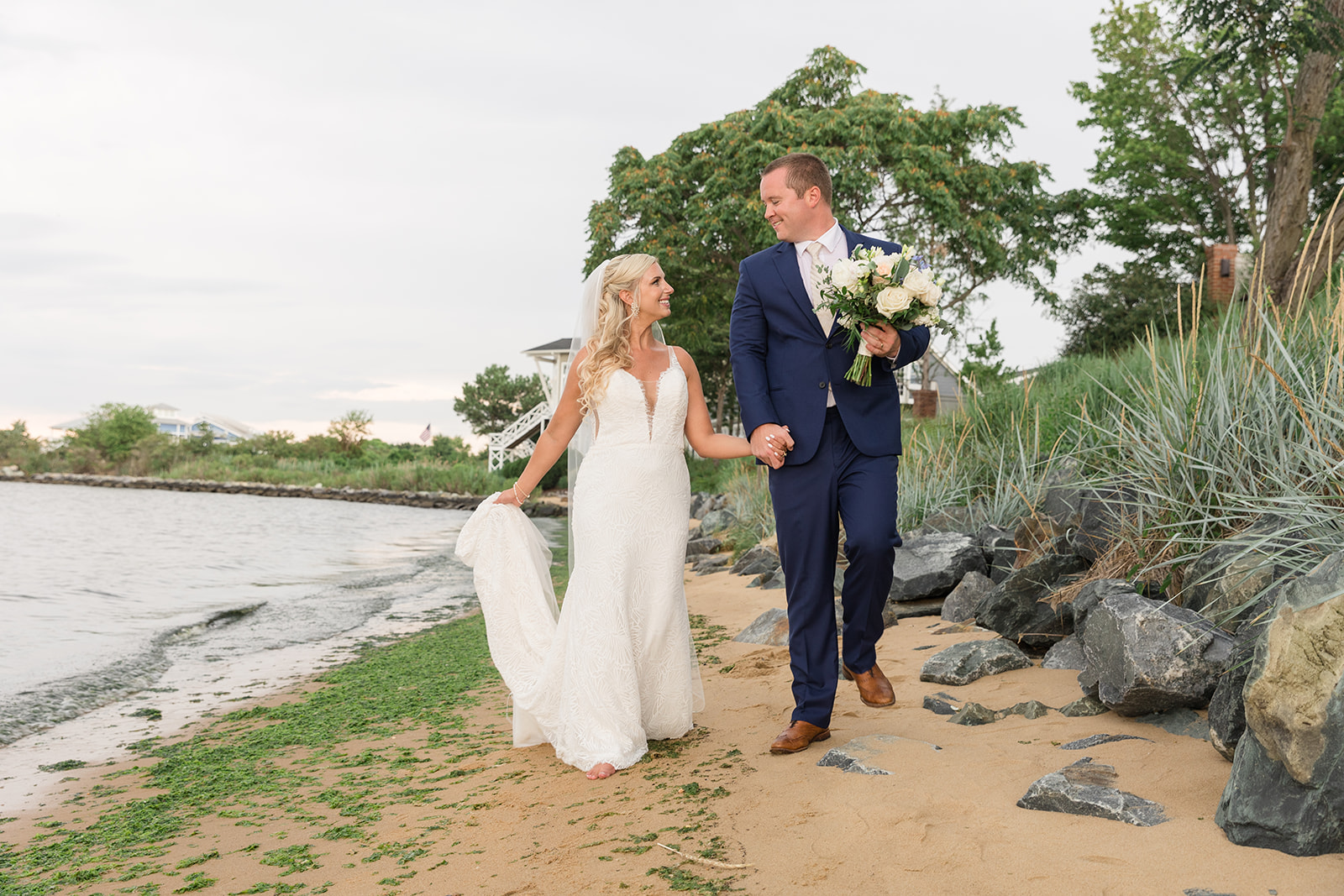 bride and groom walk along sandy beach on chesapeake bay