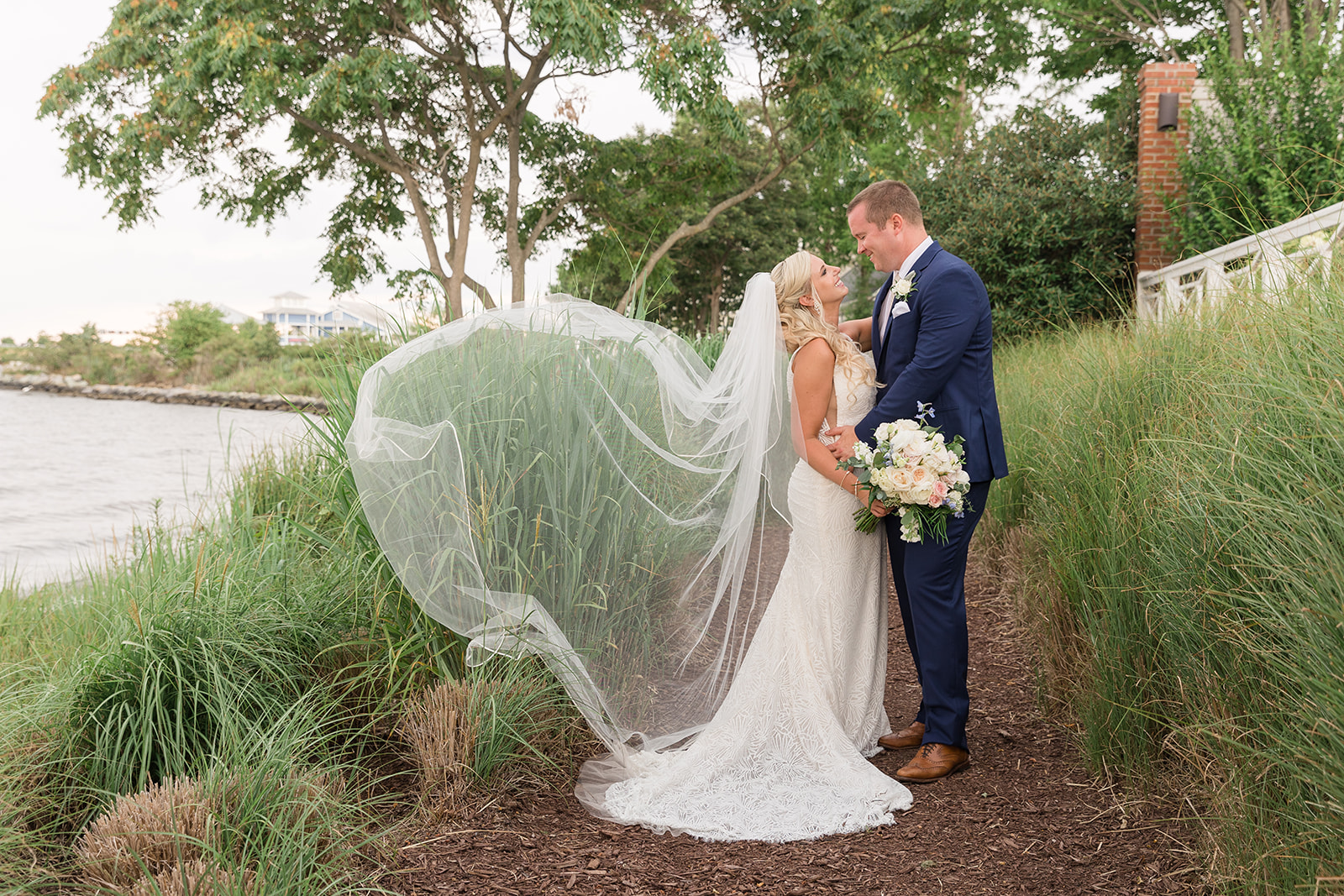 bride and groom at chesapeake bay beach club with veil blwoing in the wind