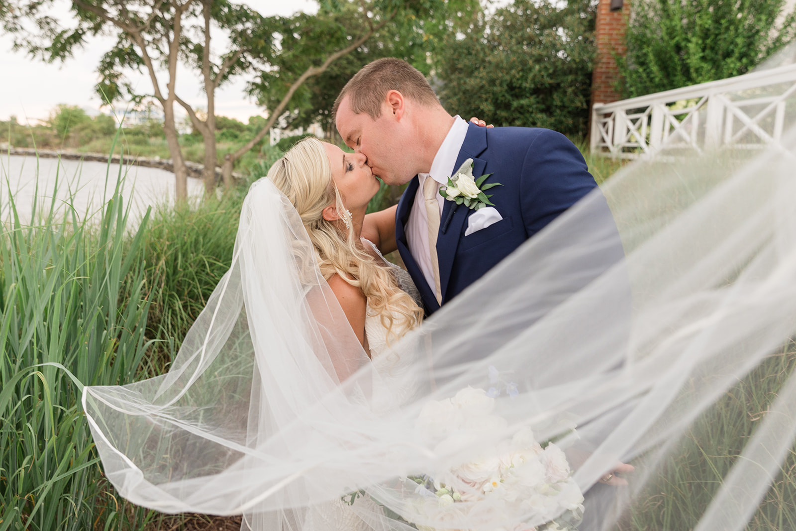 bride and groom portrait kissing with veil blowing toward camera