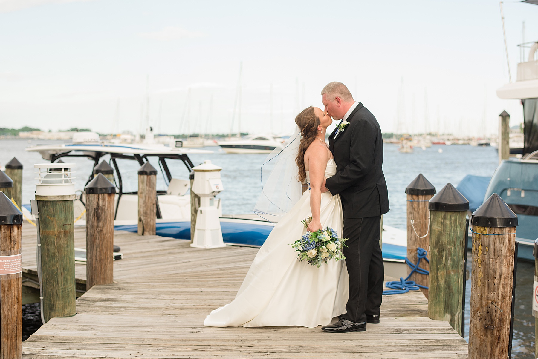 bride and groom kiss on annapolis dock