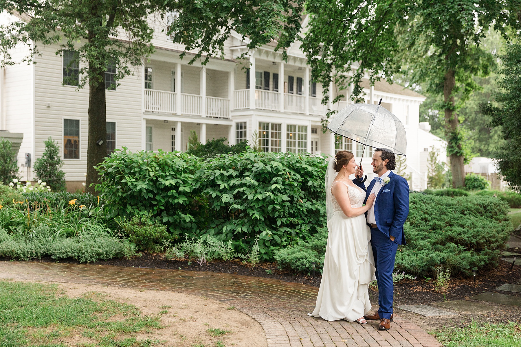 bride and groom embrace under umbrella